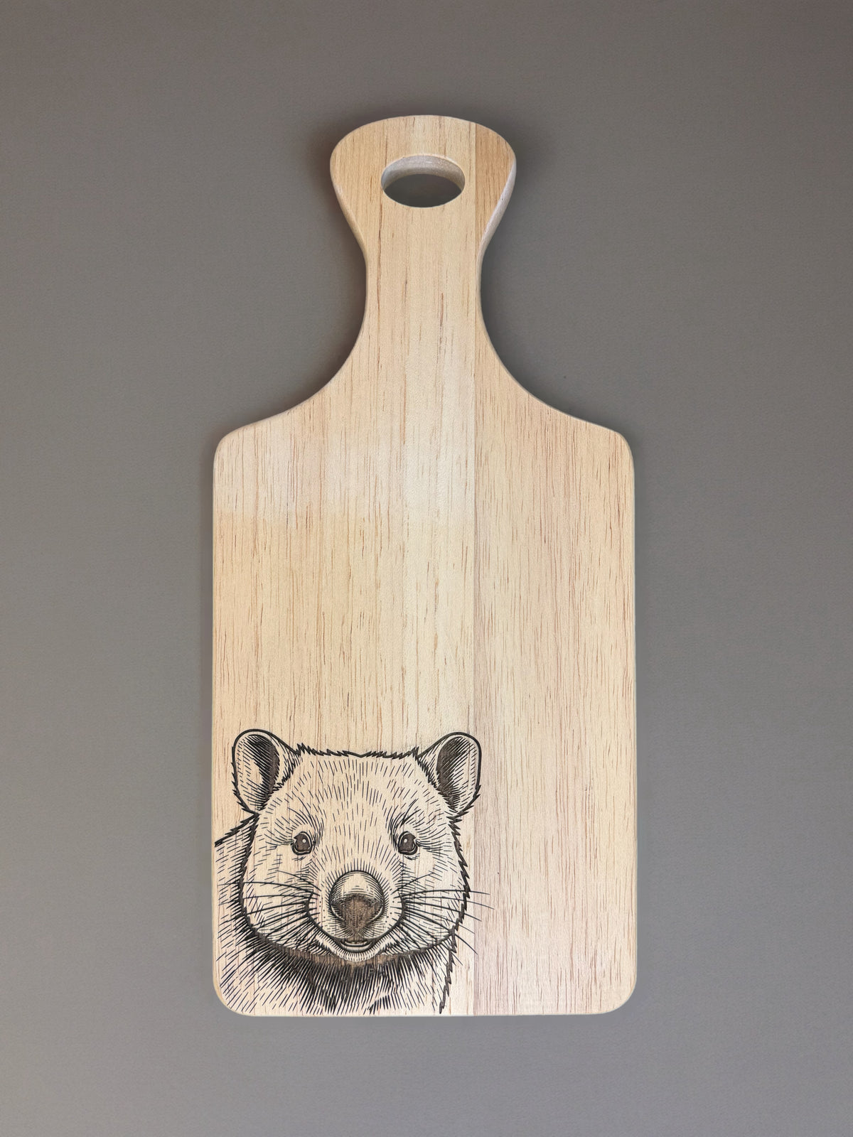 A light natural wood cutting board with a handle, featuring a detailed black ink sketch of a ferret on the lower half, set against a solid gray background.